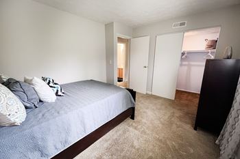 A bedroom with a bed, carpet, and two doors.